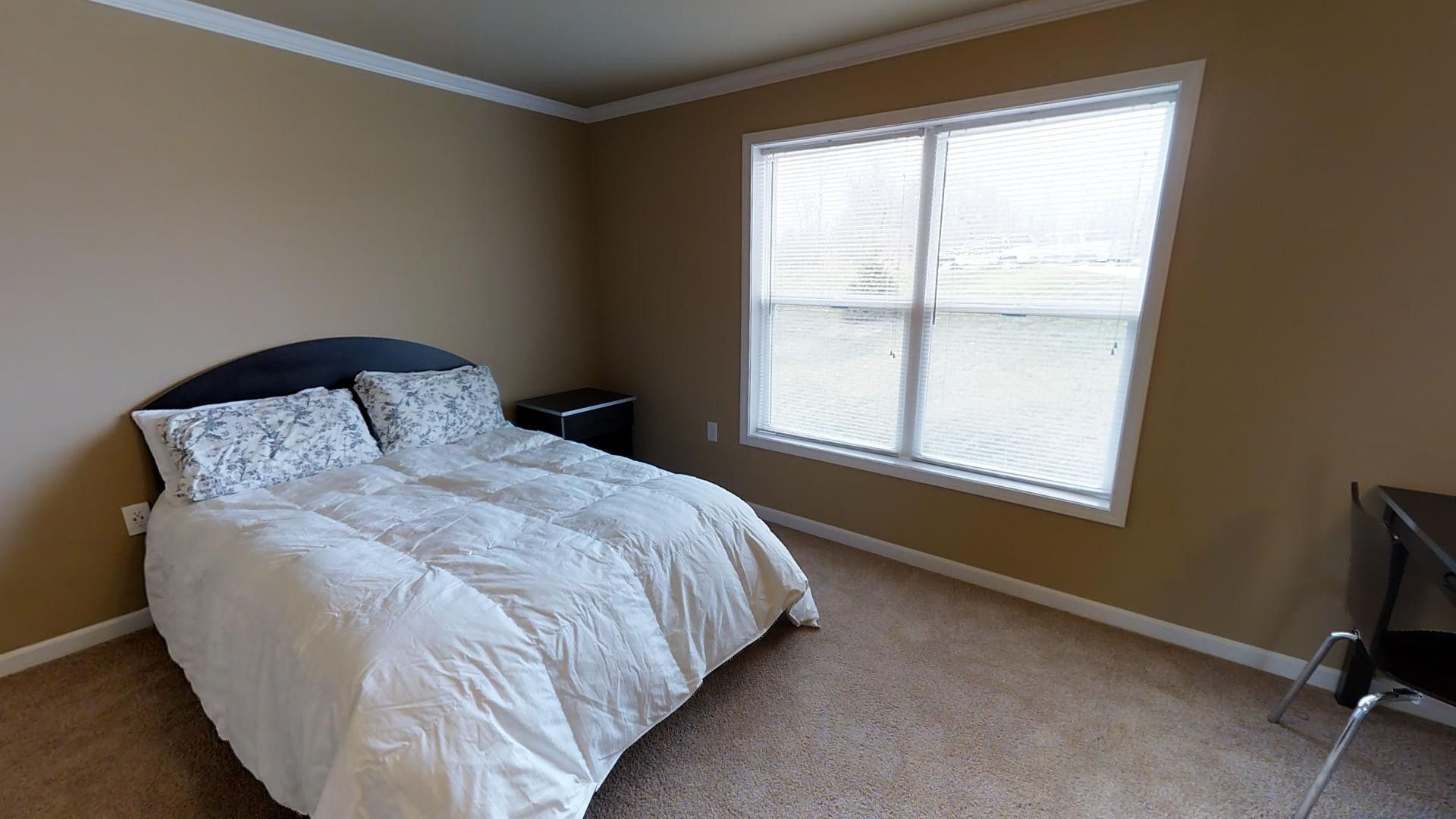 A bedroom with a bed , window , desk and chair.