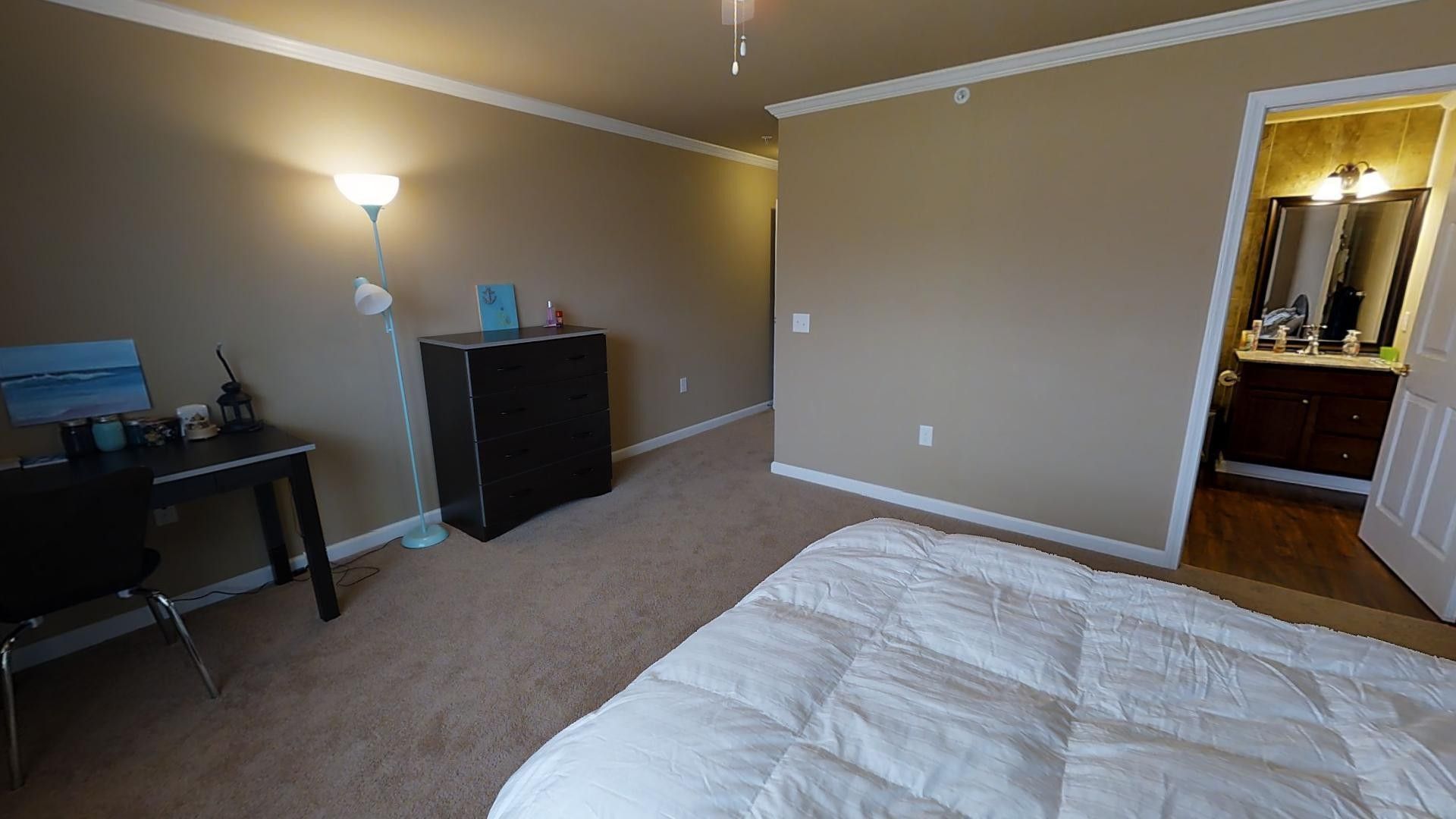 A bedroom with a bed , desk , chair and dresser.