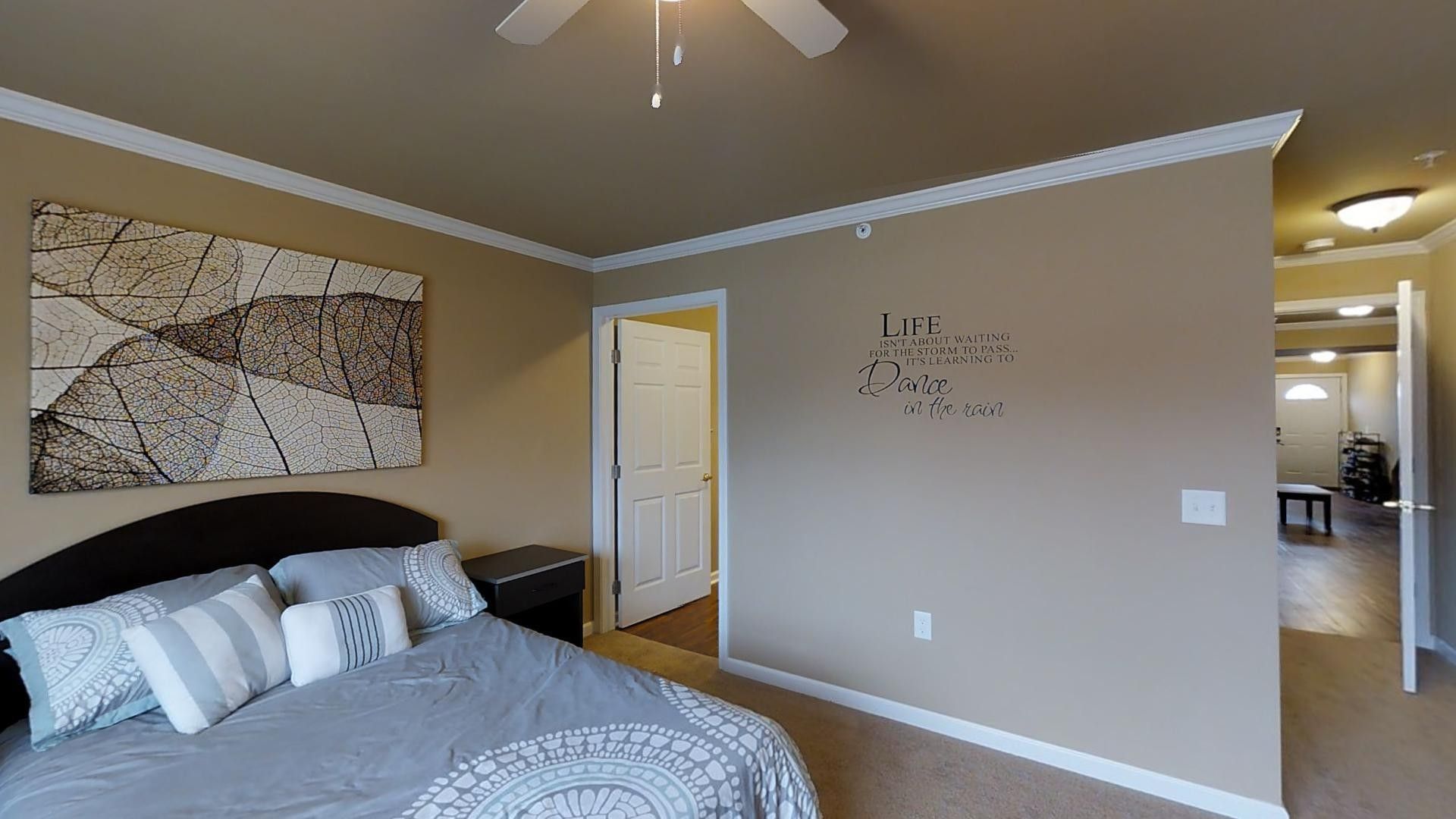 A bedroom with a large bed and a ceiling fan.