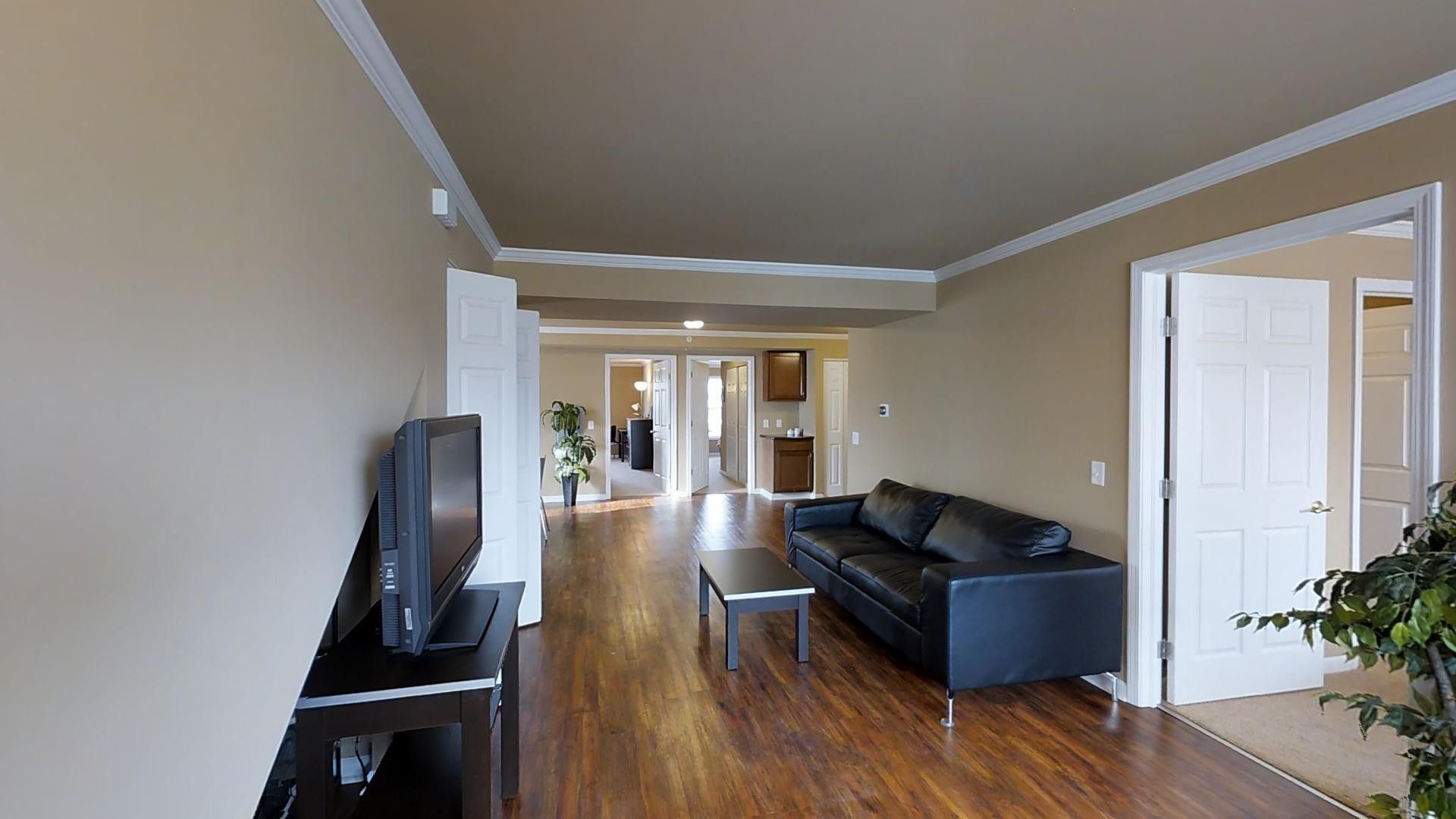 A living room with a black couch and a flat screen tv.