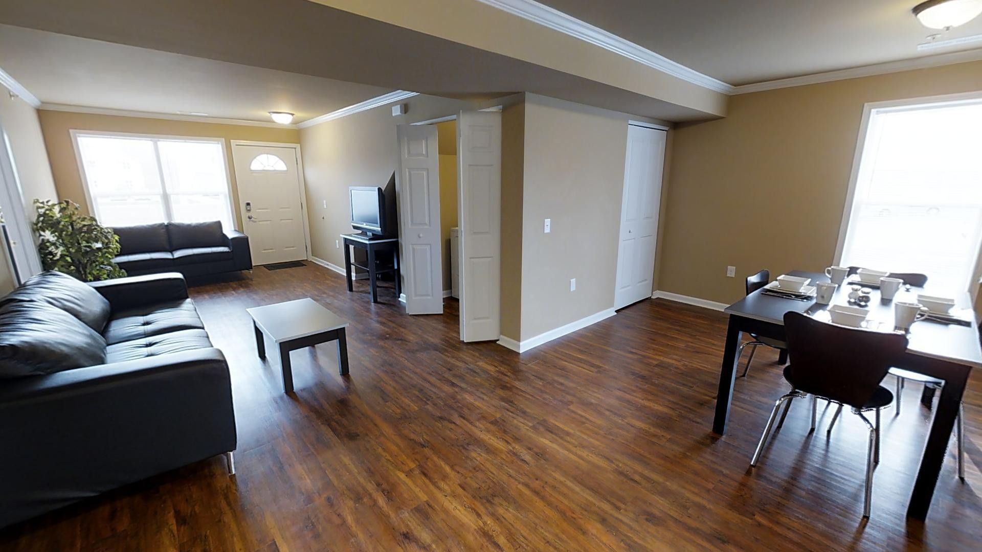 A living room with hardwood floors , a couch , a table and chairs.