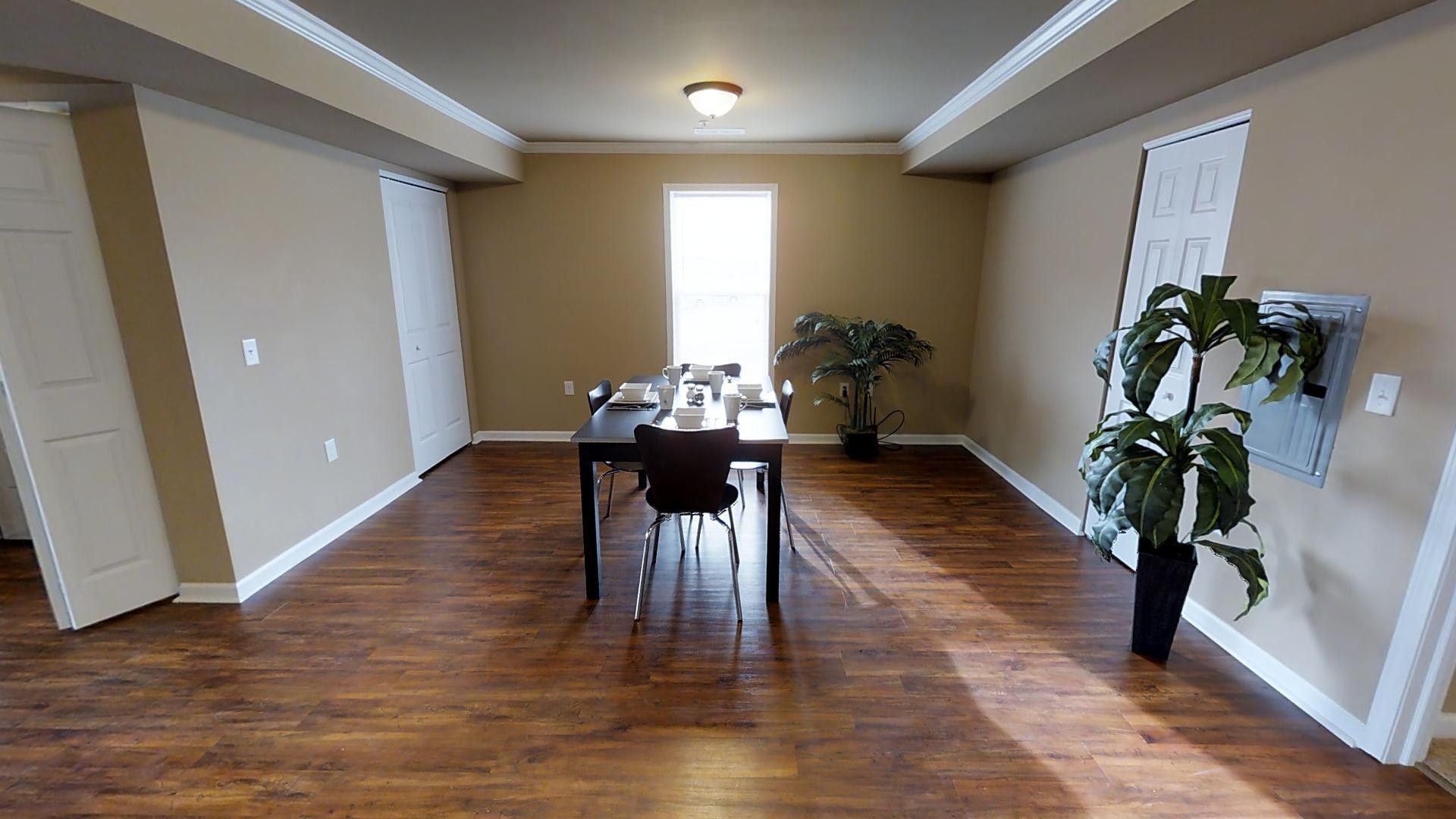 A dining room with a table and chairs and a plant.
