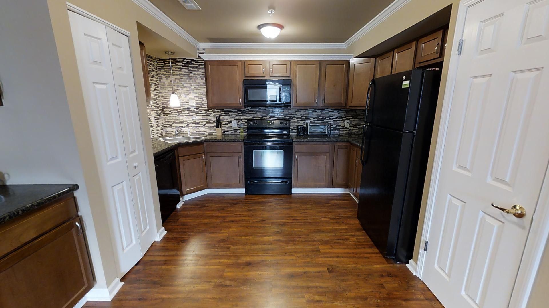 A kitchen with hardwood floors and a black refrigerator