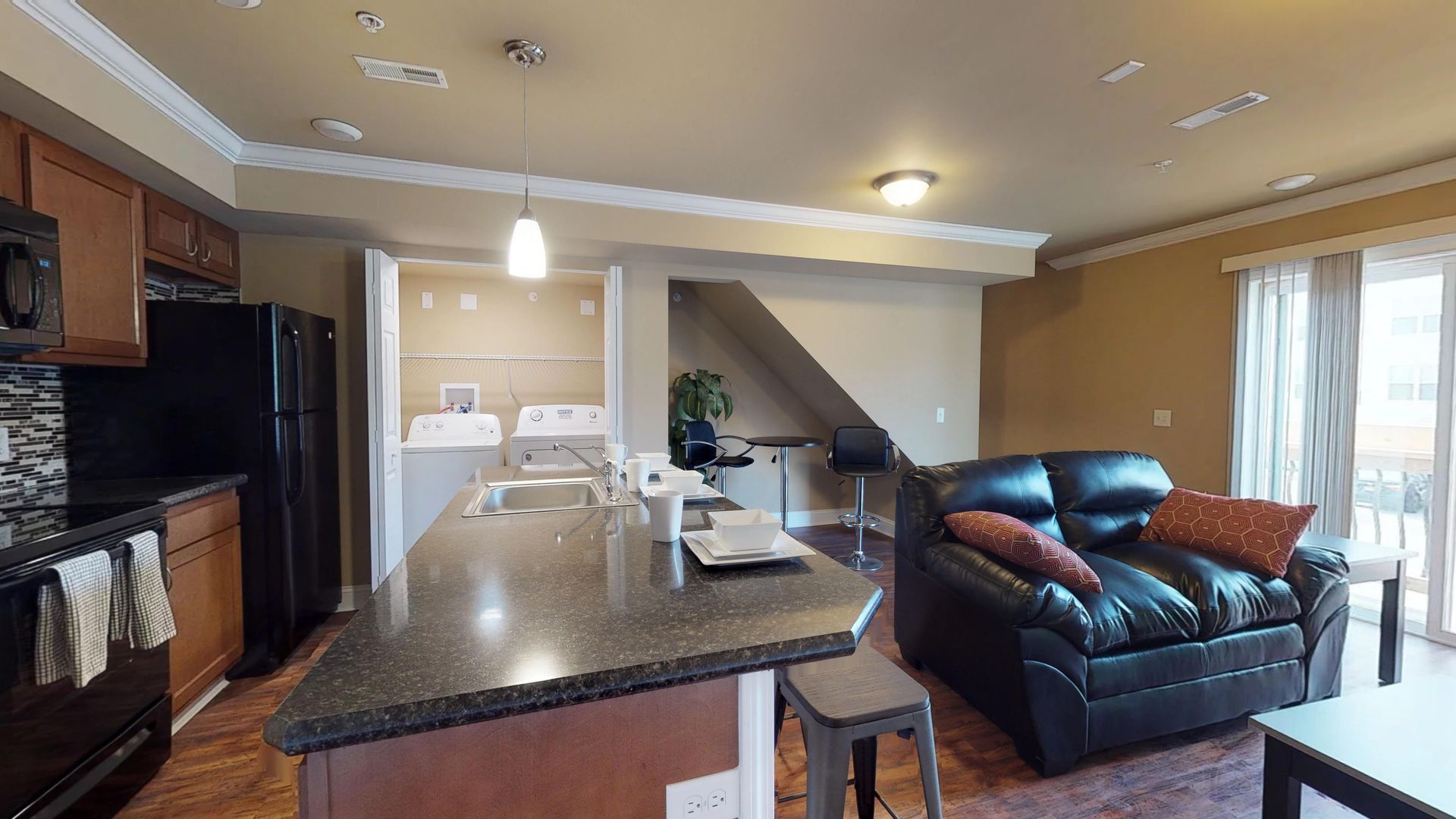 A living room with a couch and a kitchen with a refrigerator.
