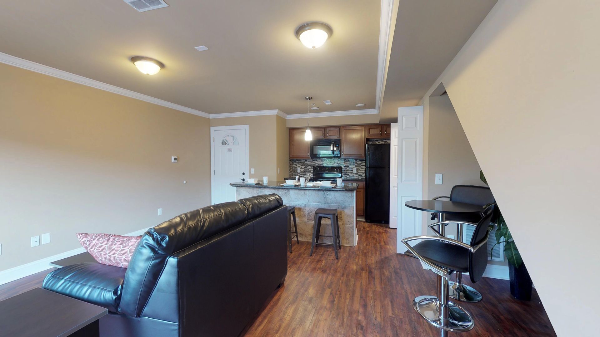 A living room with a couch , table , chairs and a kitchen.