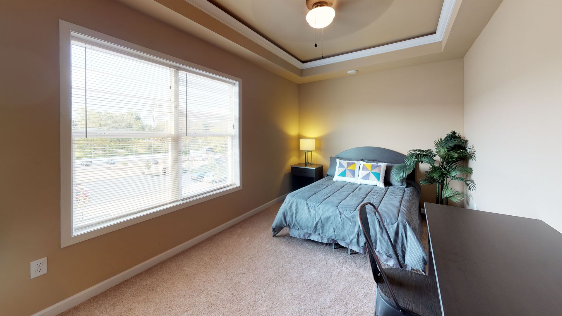 A bedroom with a bed , desk , chair and ceiling fan.