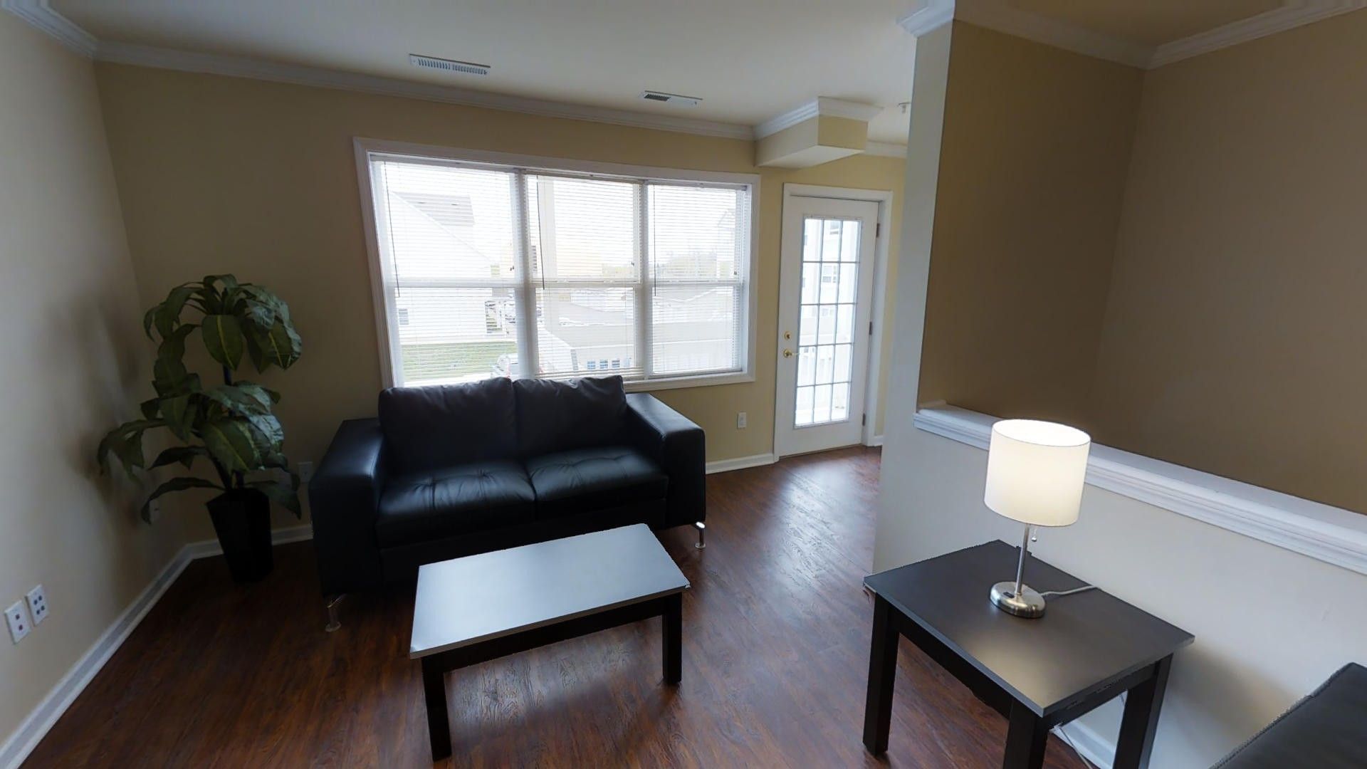 A living room with a couch , coffee table and lamp