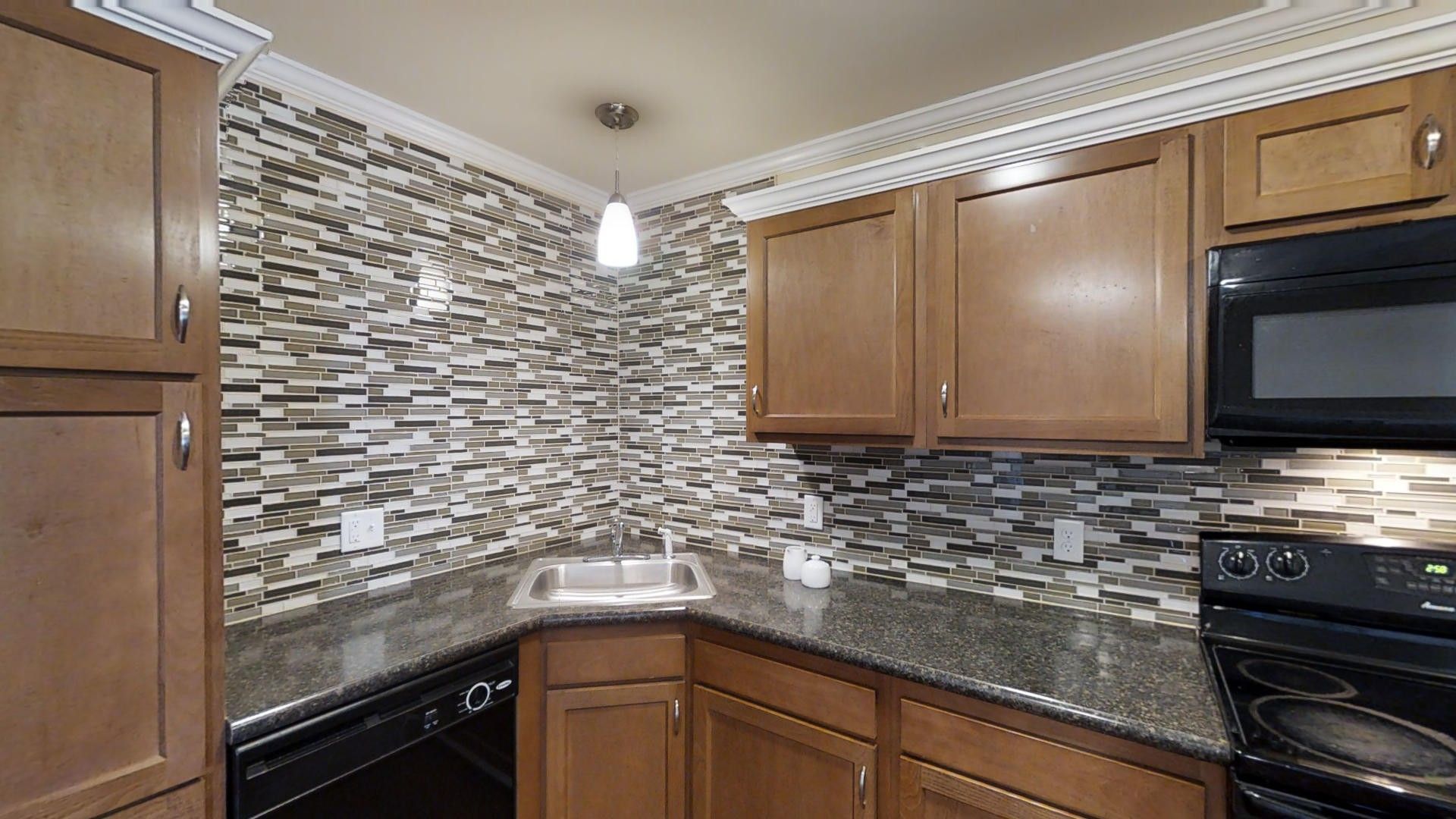 A kitchen with wooden cabinets , granite counter tops , a stove , dishwasher , and microwave.