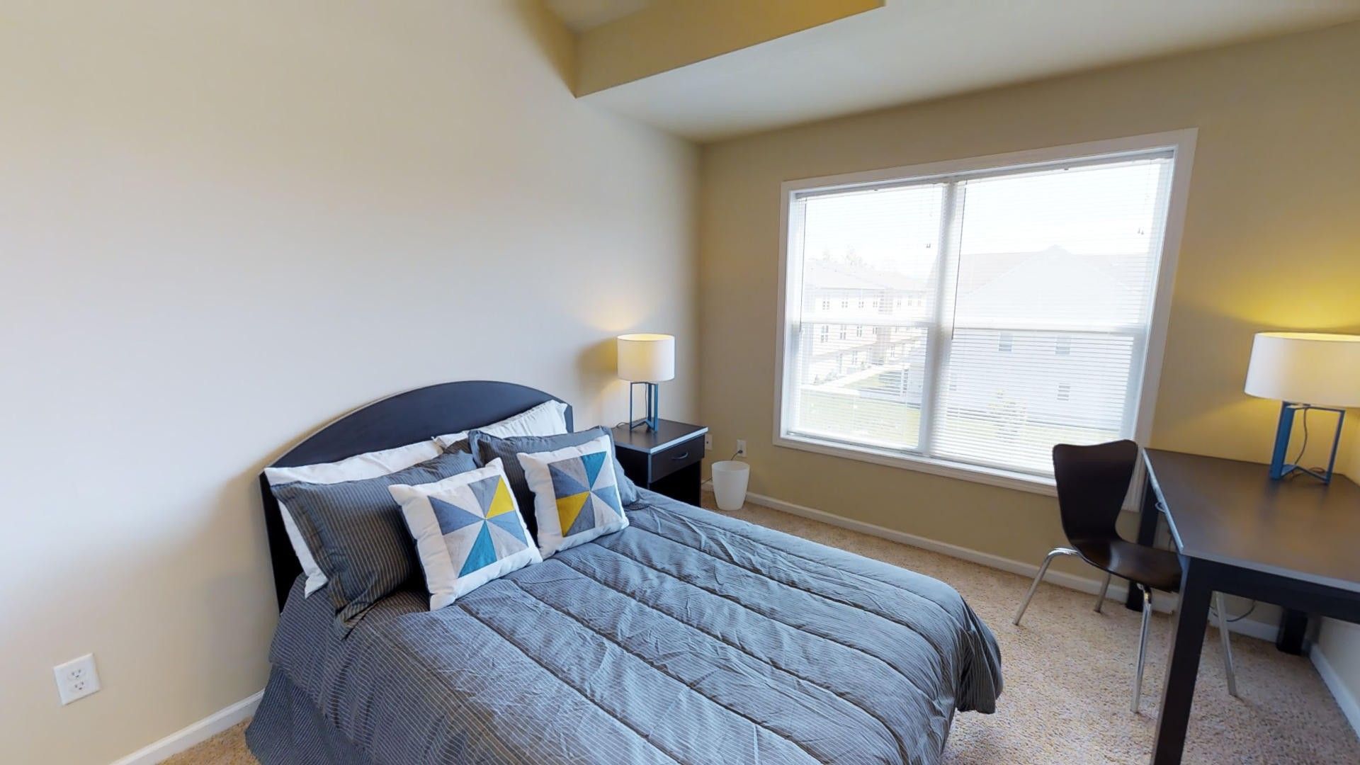 A bedroom with a bed , desk , chair and window.
