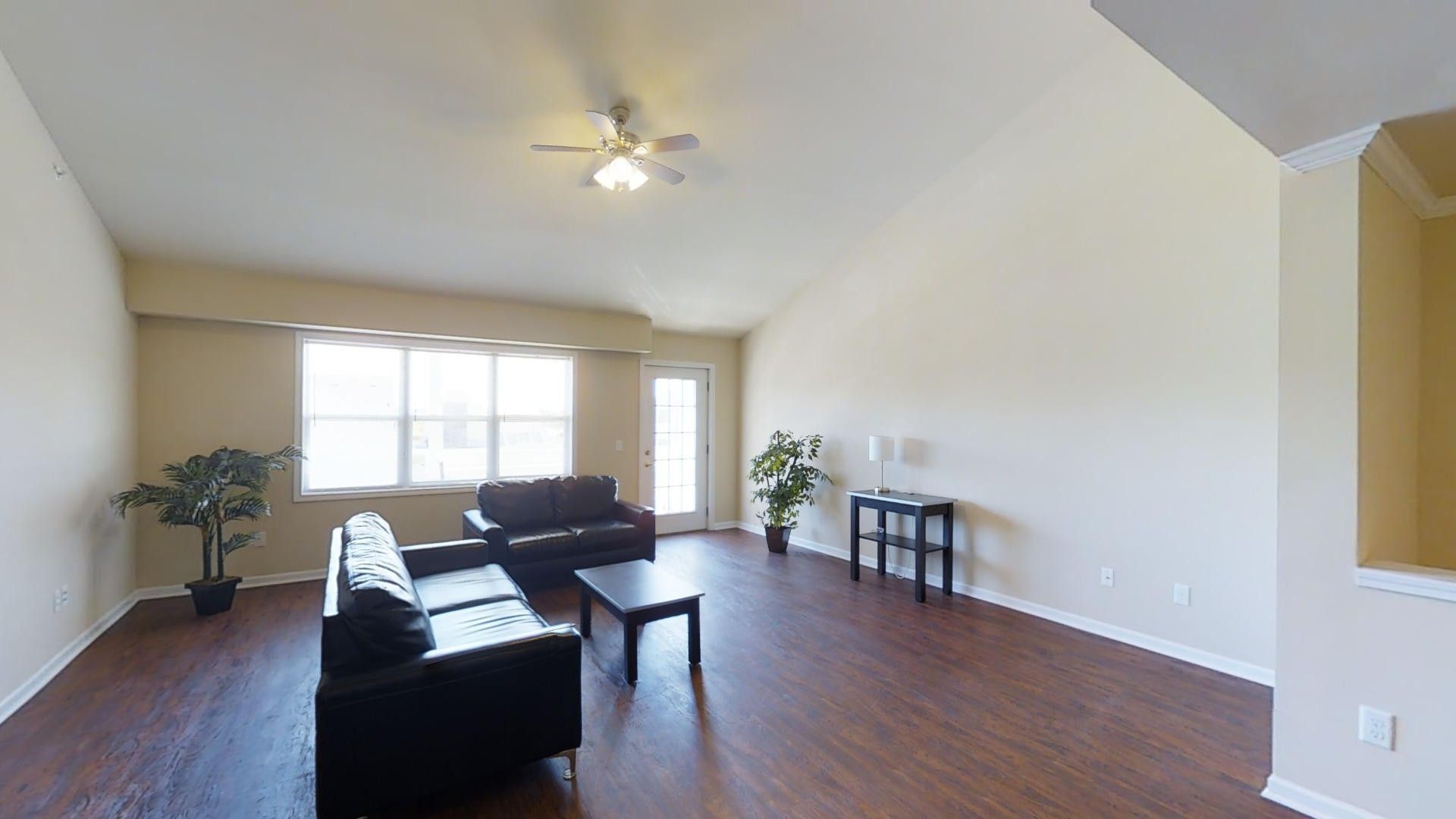 A living room with a couch , chair , coffee table and ceiling fan.