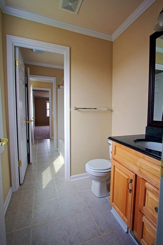 A bathroom with a toilet , sink and mirror.