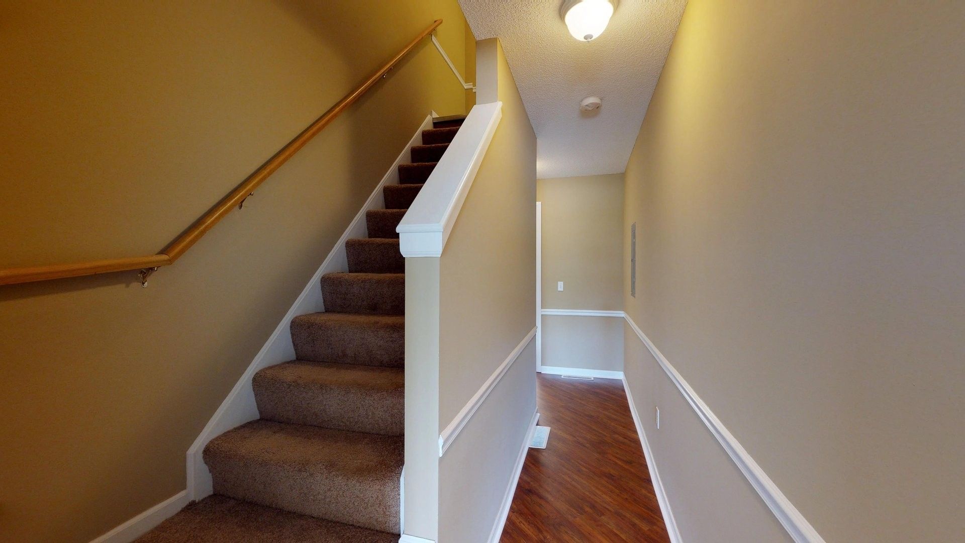 A hallway with stairs leading up to the second floor of a house.