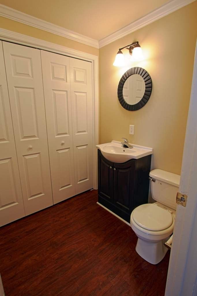 A bathroom with a toilet , sink and mirror.
