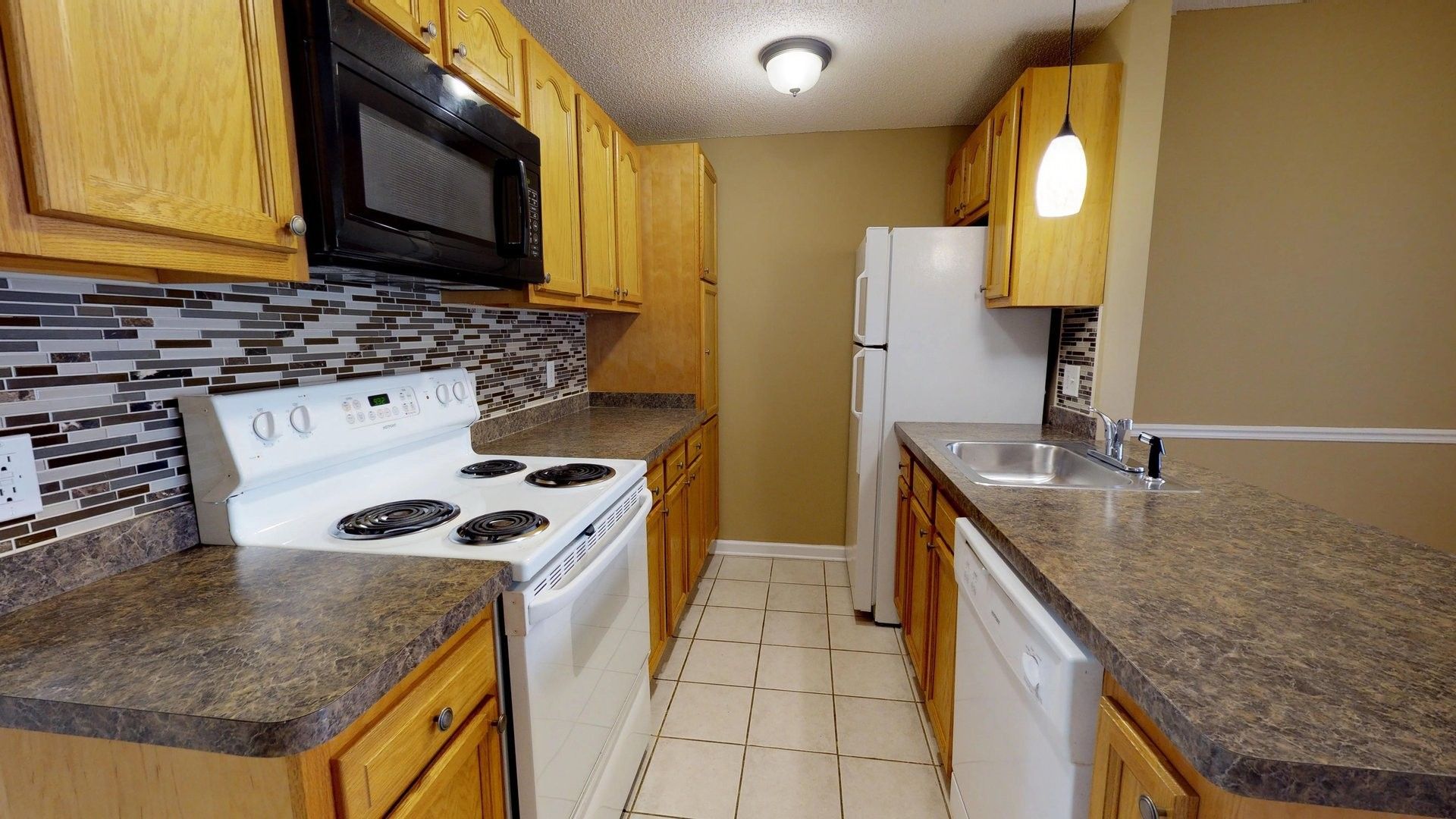 A kitchen with a stove , refrigerator , microwave and sink.