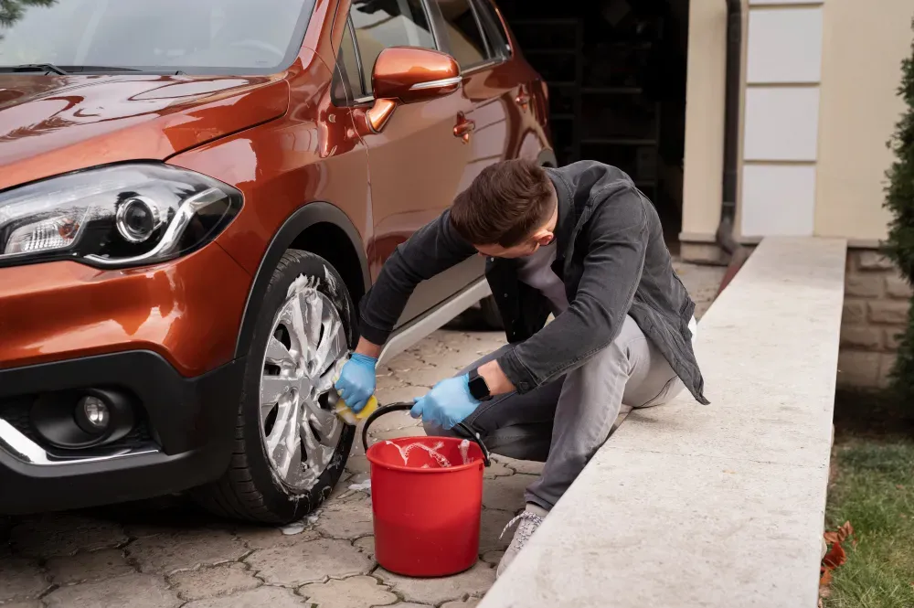A man is cleaning a car wheel with a sponge.