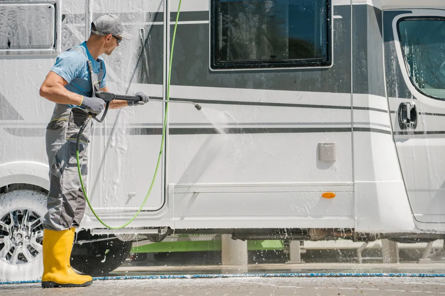 A man is washing a rv with a high pressure washer.