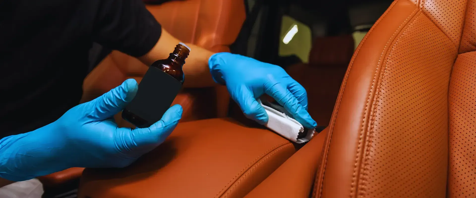 A person wearing blue gloves is cleaning the seats of a car.