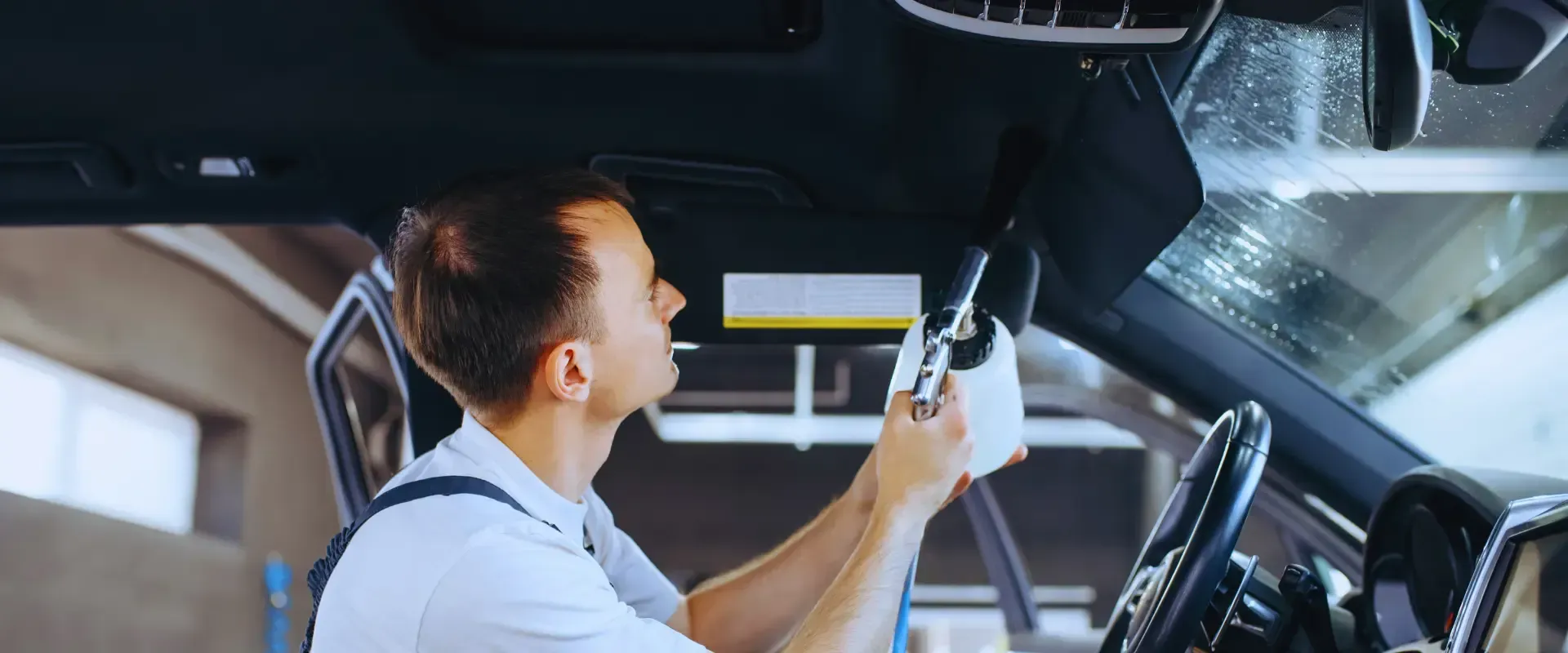 A man is cleaning the inside of a car with a cloth.