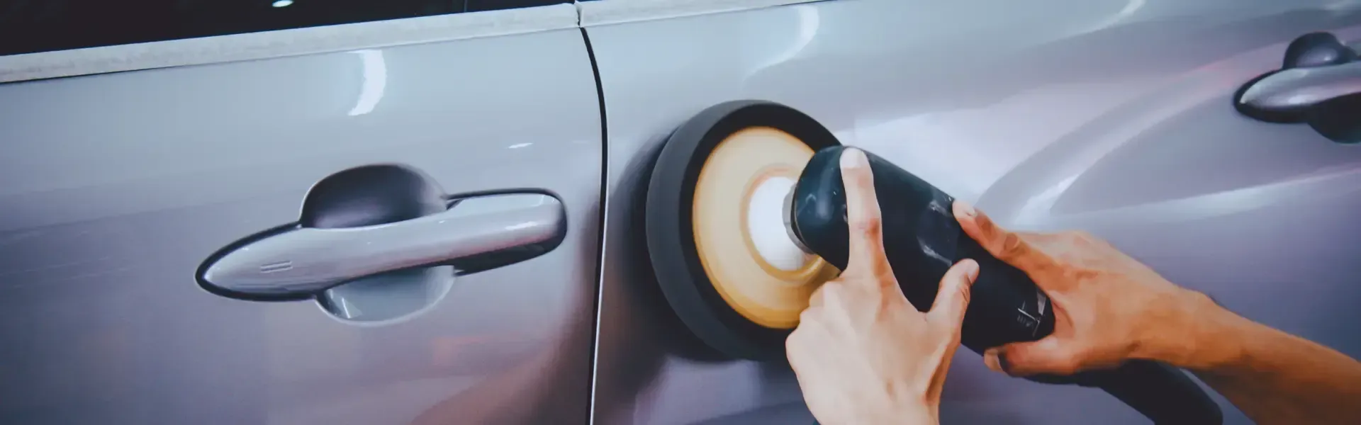 A person is polishing a car with a polisher.