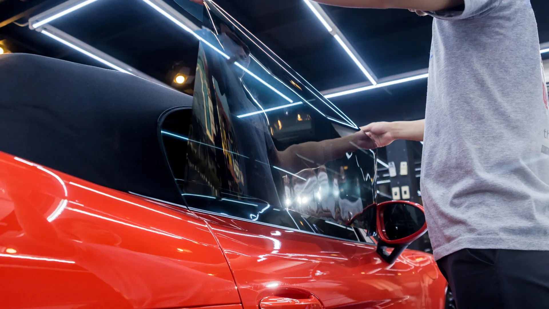 a man is applying window tinting to a red car .