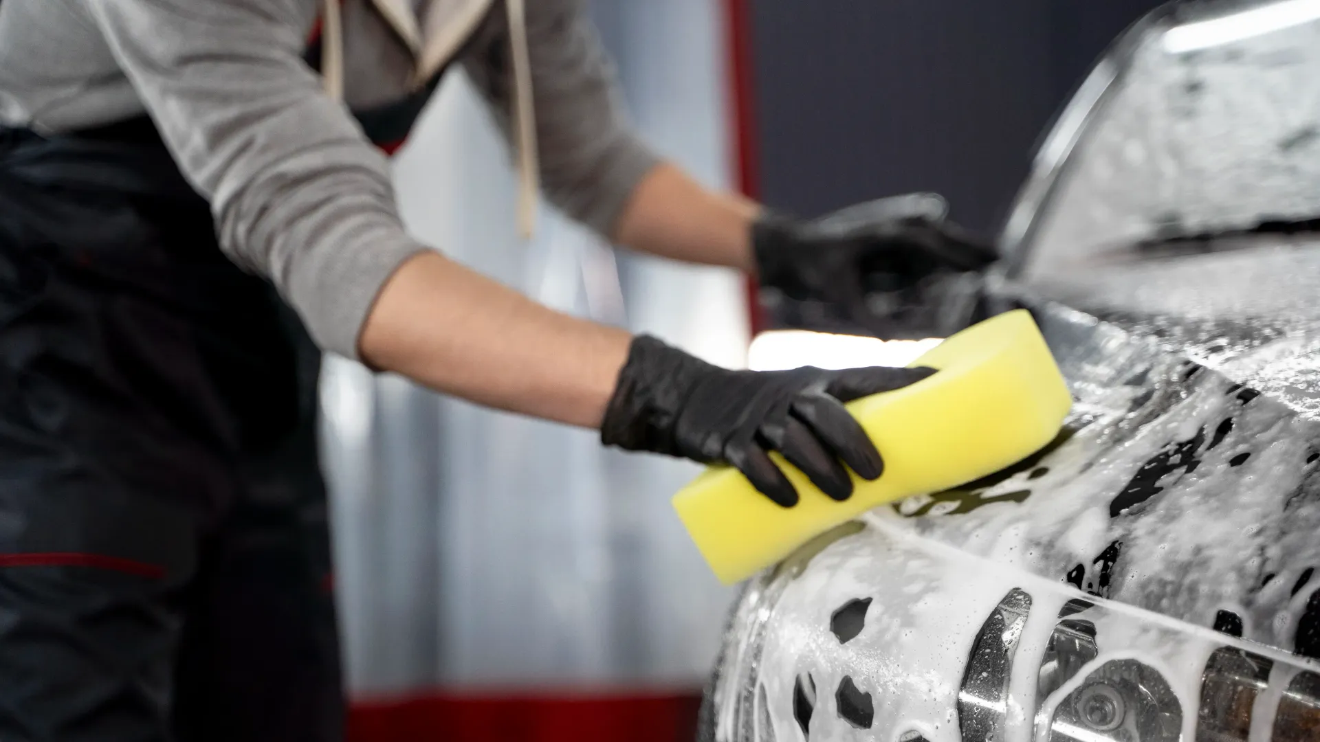 a man is washing a car with a yellow sponge .