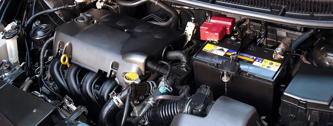 A close up of the engine of a car with the hood open.