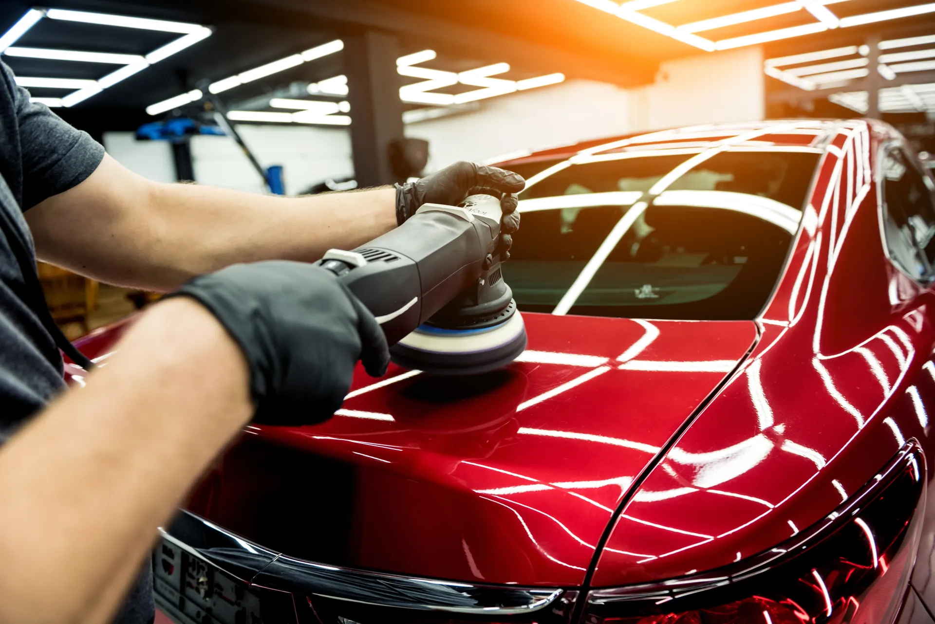 a man is polishing a red car with a machine .