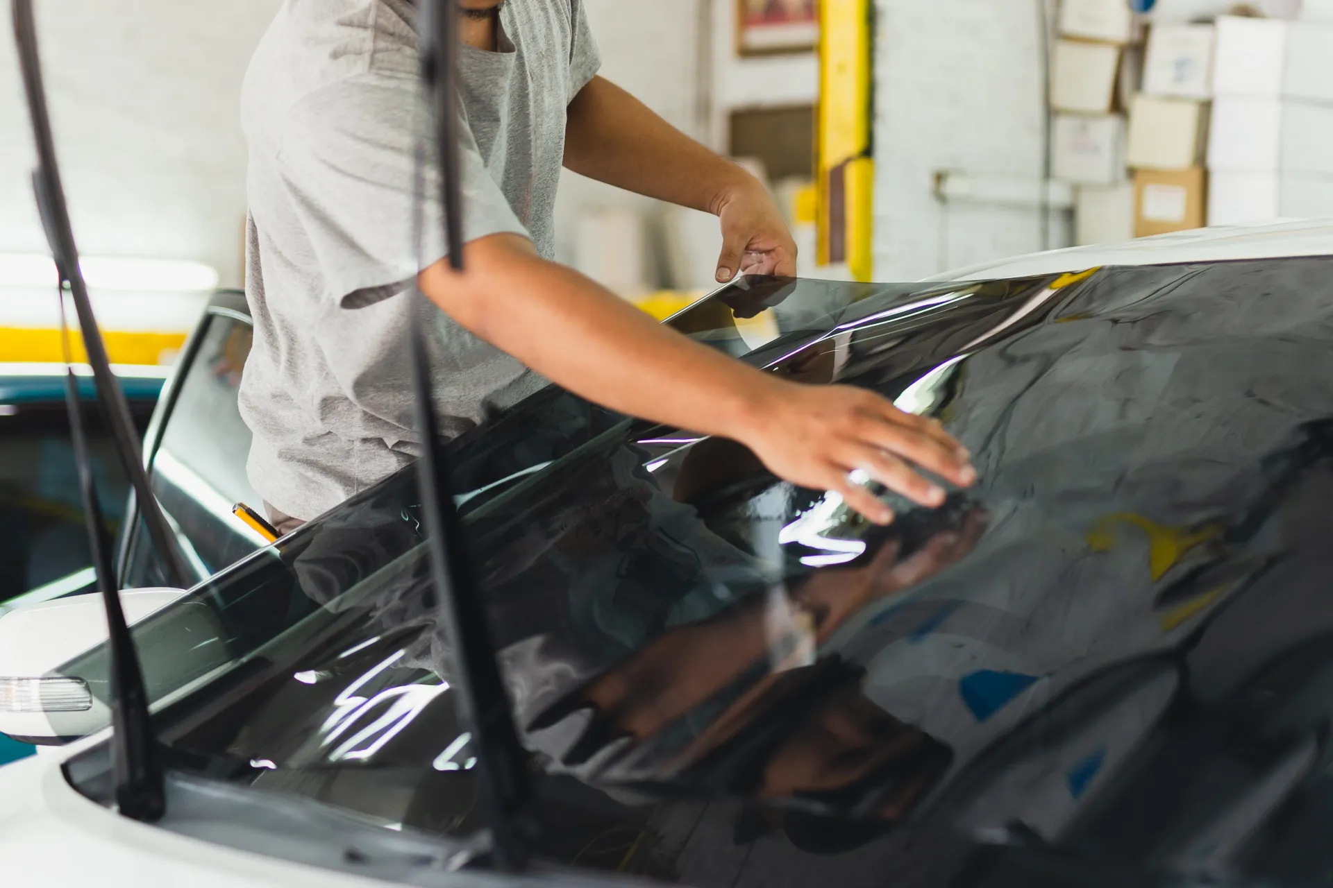 a man is applying tinted glass to a car window .