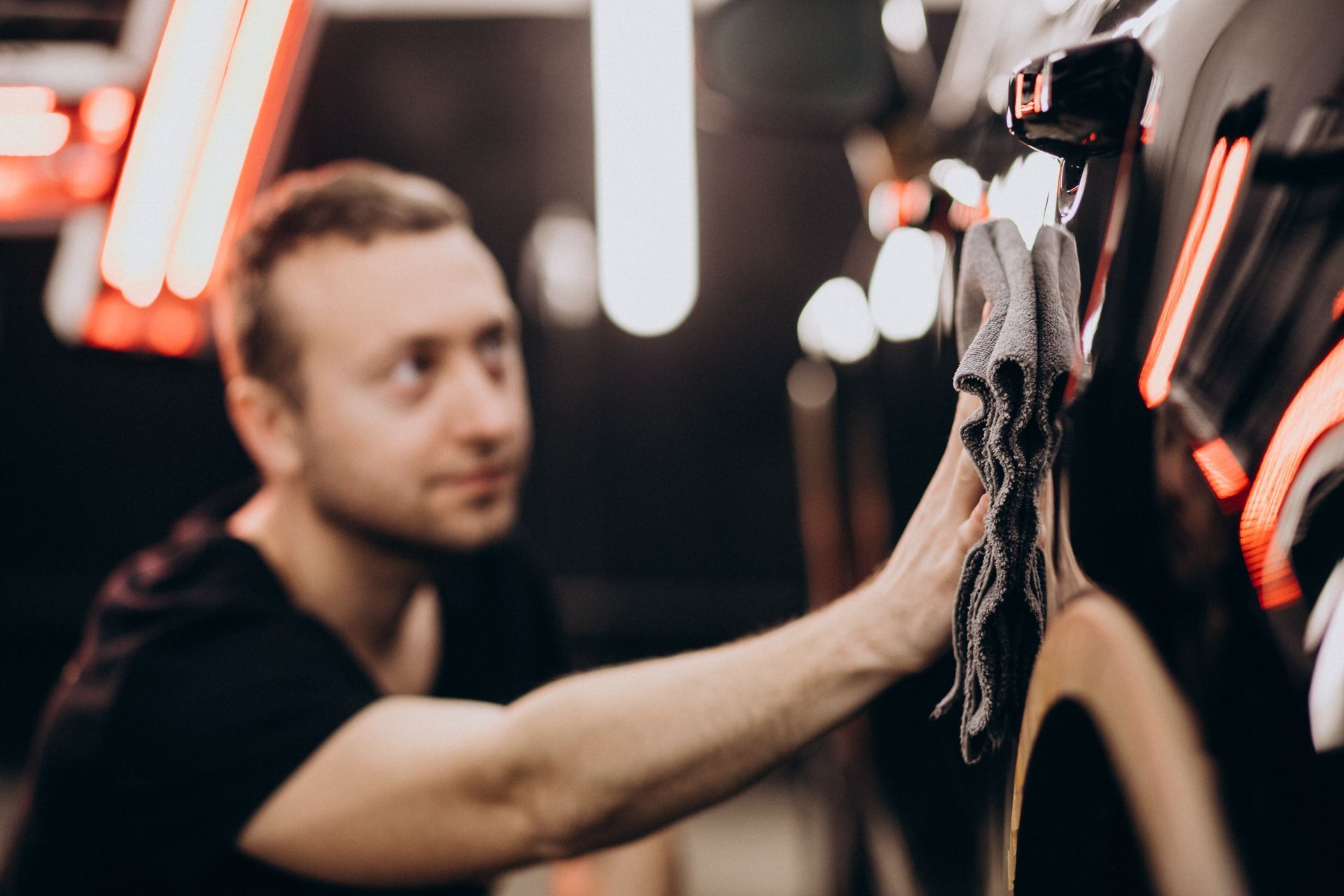 a man is cleaning a car with a towel in a car wash .