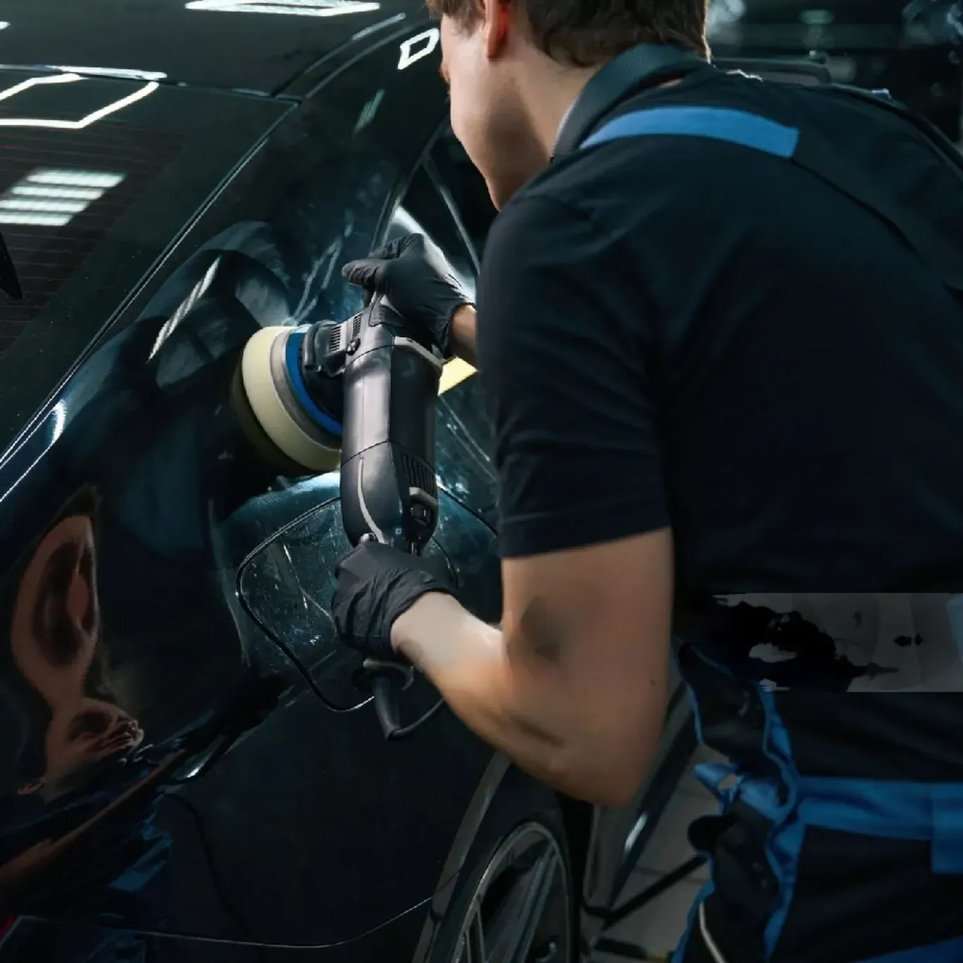 un hombre está puliendo un auto negro con una máquina