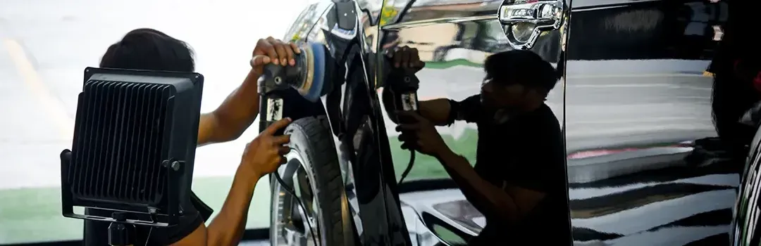A man is polishing a car in a garage.