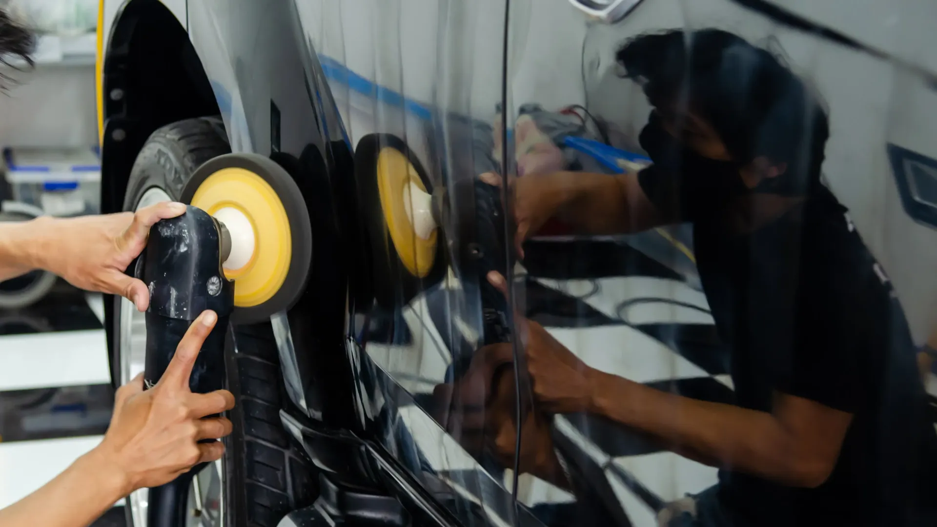 a man is polishing a car with a polisher .