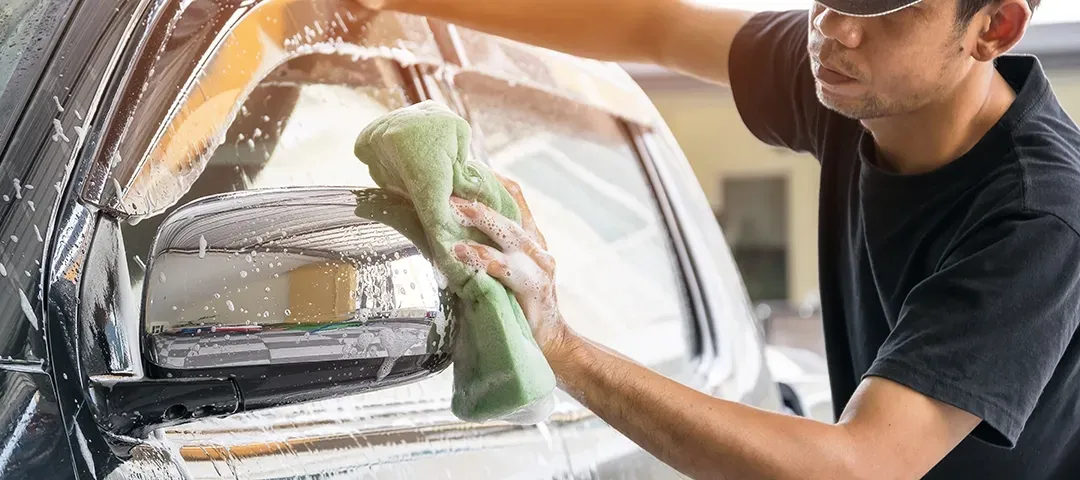 A man is washing a car with a towel.