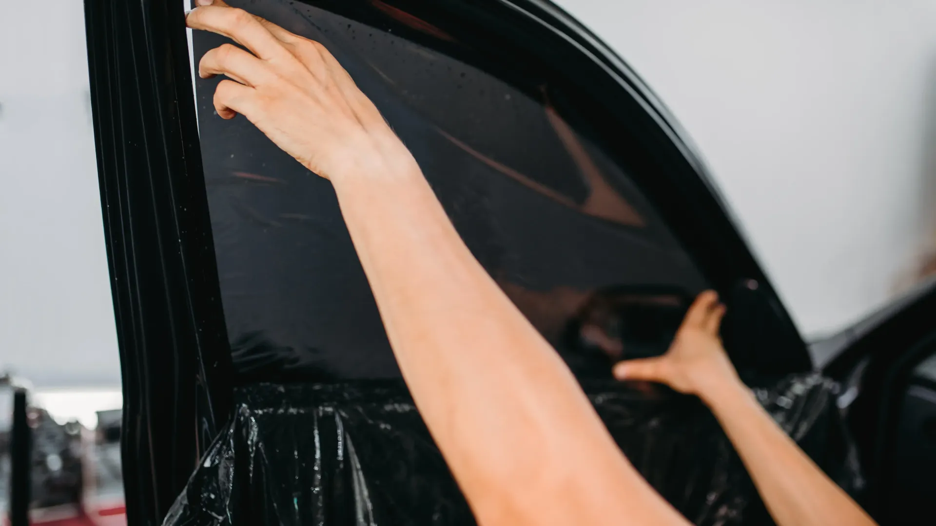 a person is applying tinted window film to a car window .