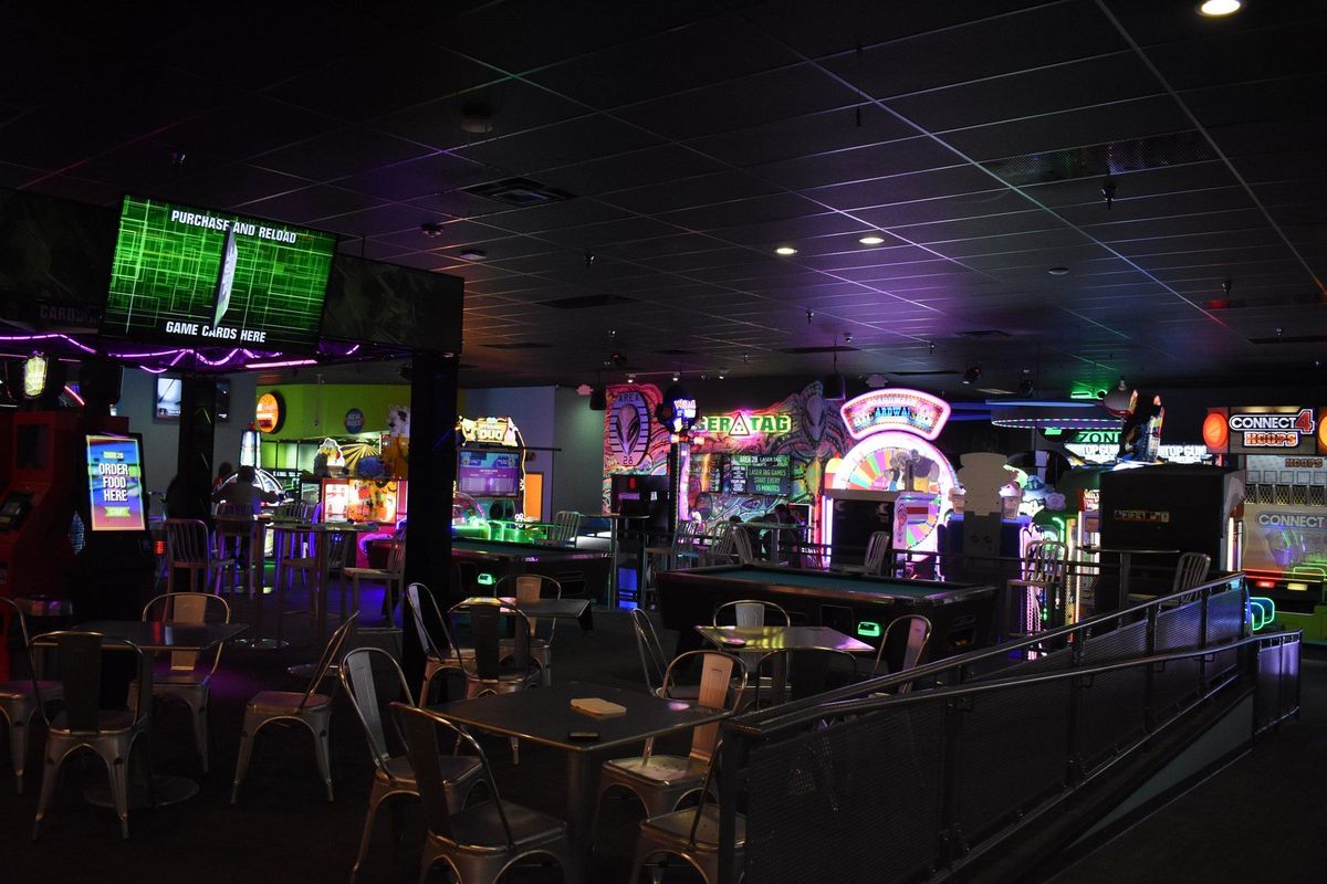 The Game Zone arcade floor at Zone 28 in Pittsburgh, lit by neon, with game cabinets and pool tables