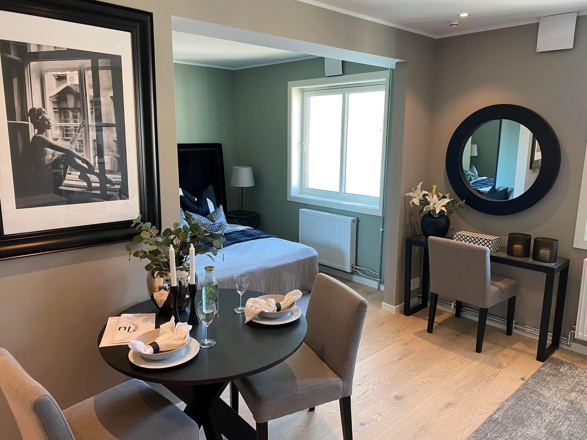 Rominteriør med et spisebord, en servant og en seng i bakgrunnen.