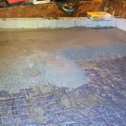 Wet concrete being spread over a wire mesh floor in a construction area