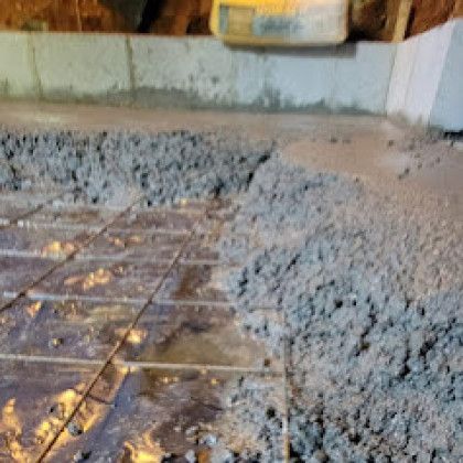 Fresh concrete being poured over tiled floor beside a wall indoors