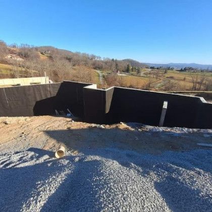 Gravel rooftop with black parapet walls overlooking a rural valley under a clear blue sky