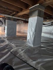 Basement with wrapped support posts, plastic floor covering, and exposed beams under the ceiling