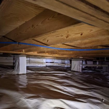 Insulated crawlspace under wooden floor joists with a blue cable running across the ceiling