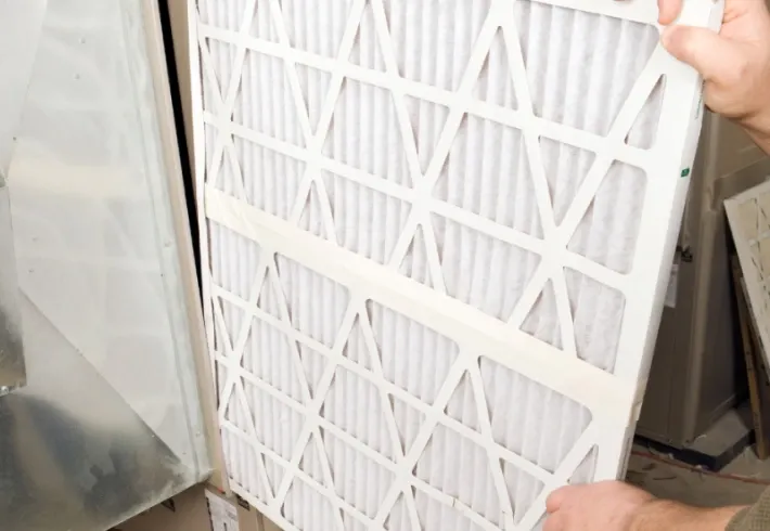 Person holding a white pleated air filter in a workshop area