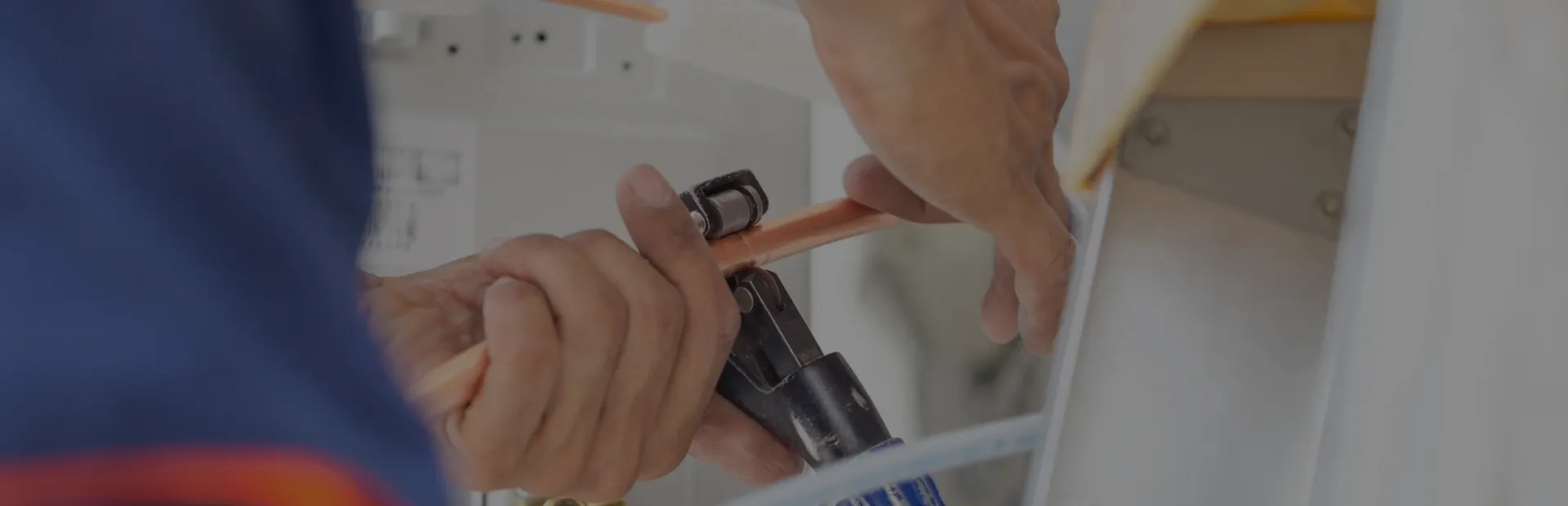 Hands connecting black wires with a copper connector inside a white electrical box