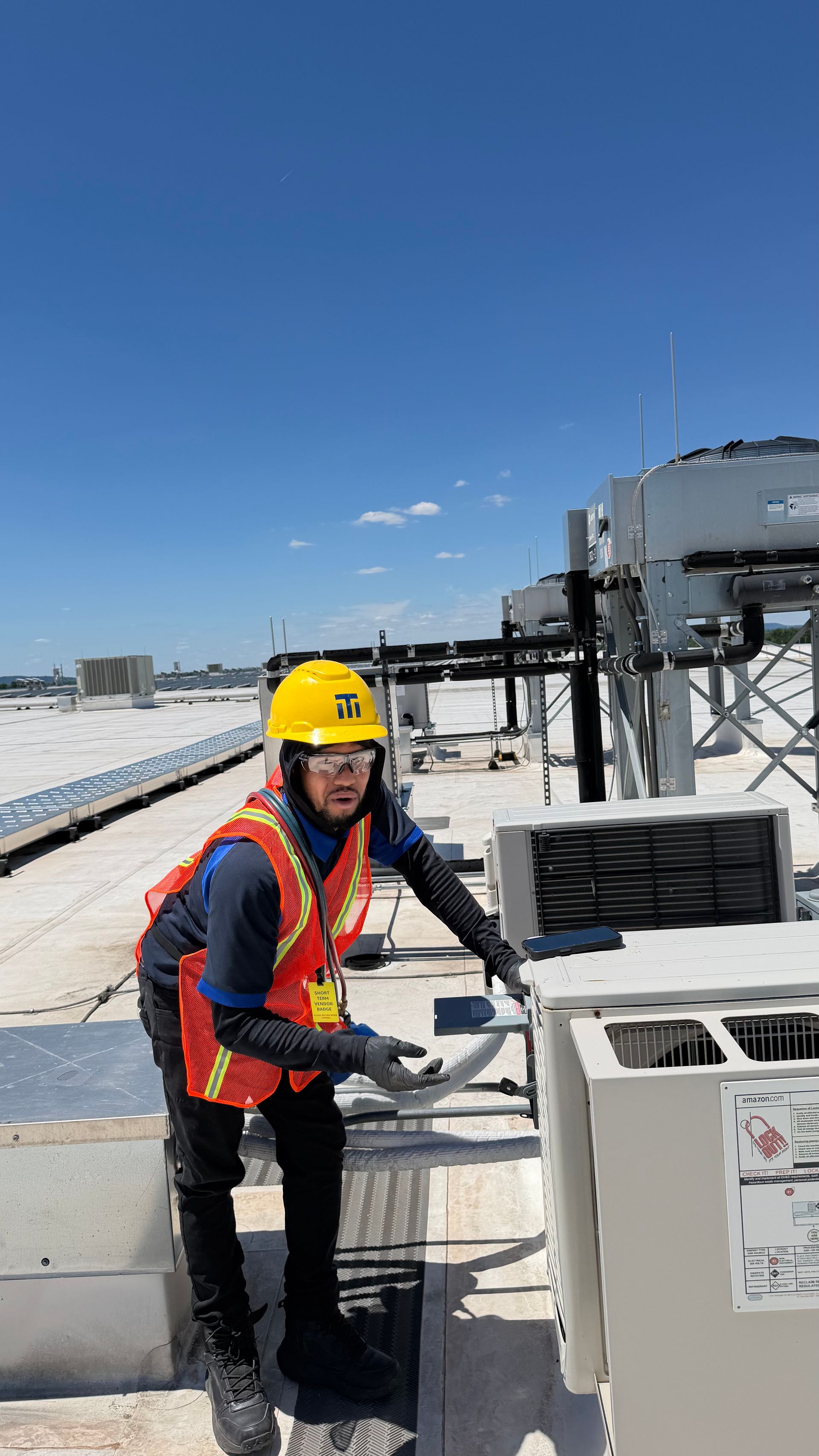 Multiple commercial rooftop HVAC units with large silver ventilation ducts under a clear sky