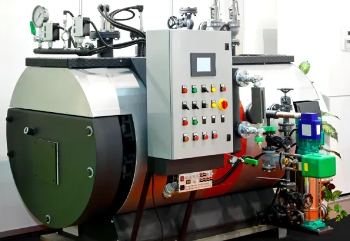 Industrial boiler with control panel and attached piping in a factory setting