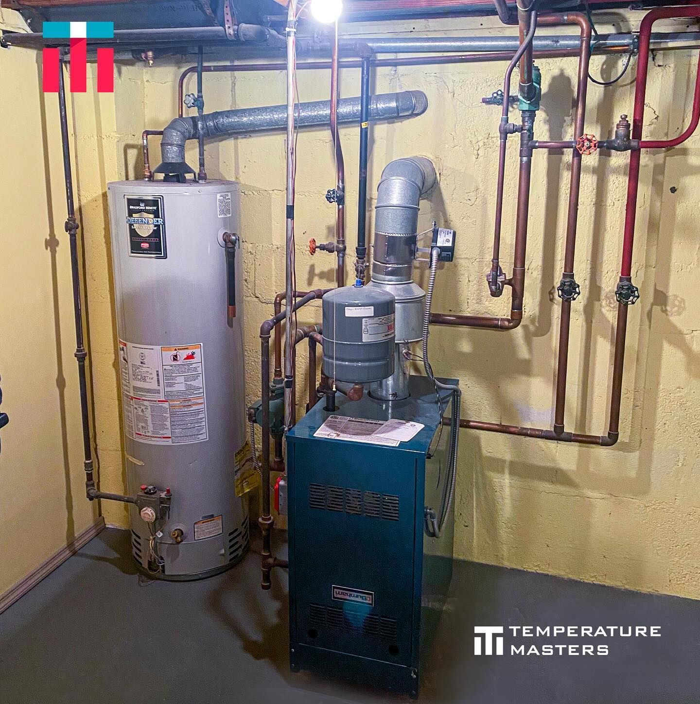 Basement utility room with water heater, furnace, and exposed plumbing against yellow walls.