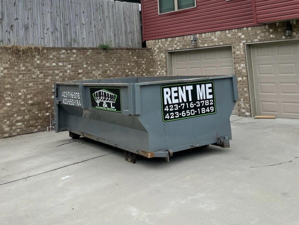 A dumpster is parked in front of a building that says rent me.