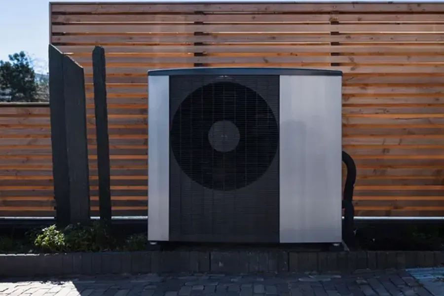 Outdoor HVAC unit beside a wooden slat fence on a paved patio.