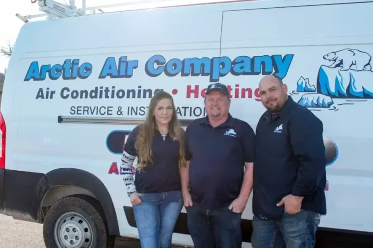 Three people standing in front of an Arctic Air Company service van.