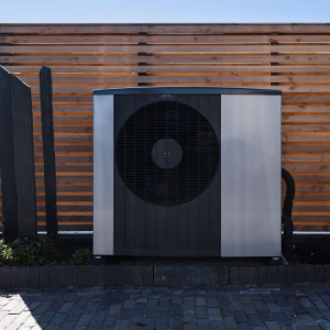 Outdoor HVAC unit beside a wooden slat fence on a paved patio.